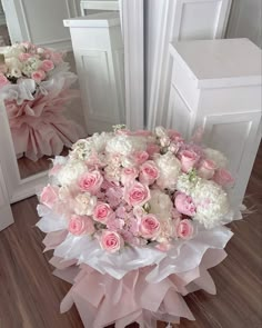 a bouquet of pink and white flowers sitting on top of a wooden floor next to a mirror