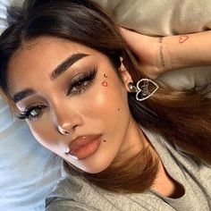 a woman laying on top of a bed with her nose piercing in the shape of a heart