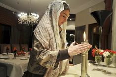 a woman standing in front of a table holding a candle