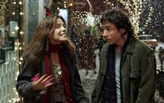 two people standing in front of a store window on a snowy day with snow falling