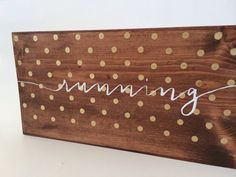 a wooden sign that says running with gold dots on it and the word running written in cursive writing