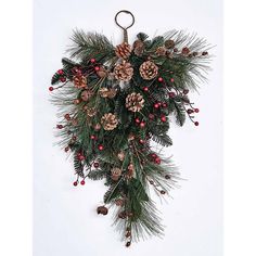 a christmas wreath hanging on the wall with pine cones and berries