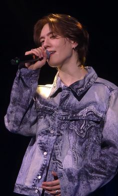 a woman in a denim jacket singing into a microphone