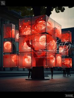 an artistic display in the middle of a street with people walking around it and red lights on