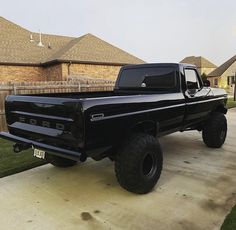 a black pickup truck parked in front of a house on a driveway next to grass