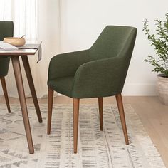 two green chairs sitting on top of a rug next to a table with a potted plant