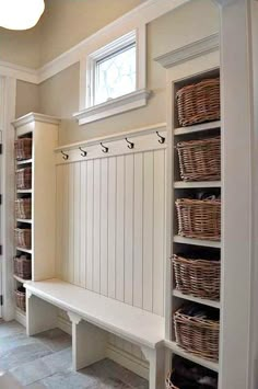 an entryway with baskets on the wall and shelves in front of it that are built into the floor