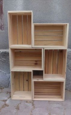 four wooden boxes stacked on top of each other in front of a brick wall and cement floor