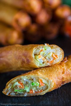 two vegetable spring rolls on a table next to some dipping sauce