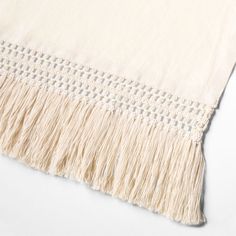 a white blanket with fringes on top of it and an embroidered border around the edges