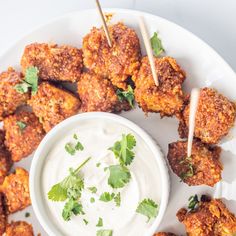 a white plate topped with tater tots covered in ranch dressing and garnished with cilantro