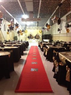 a banquet hall with black tables and gold tablecloths on the floor, along with red carpet