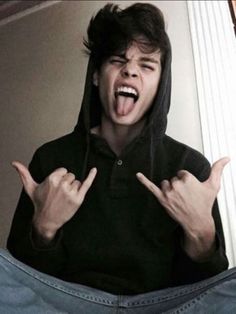 a young man with his hands in the air and making two fingers up while wearing a black hoodie