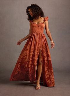 a woman in an orange dress is posing