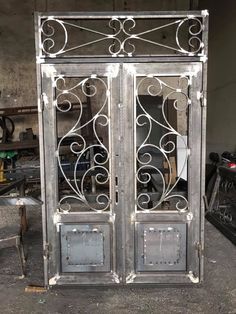 an old metal door with intricate designs on it's sides and glass doors that are open