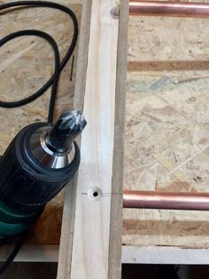 an electric drill is sitting on top of some plywood planks with a cord attached to it