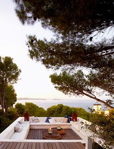 an outdoor living area with white couches and wooden flooring, overlooking the ocean