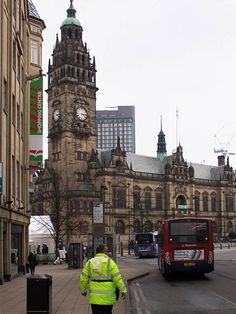 a man walking down the street in front of an old building with a clock tower