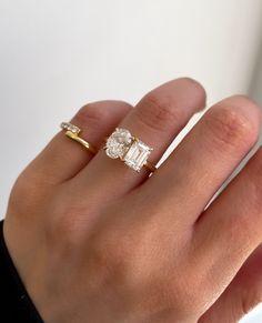 a woman's hand with a ring on it and an engagement ring in the middle