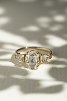 a close up of a ring with a diamond on the top and two side stones in the middle