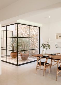 a dining room with a table and chairs in front of a glass wall that looks out onto the outdoors