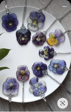 a white plate topped with lots of purple and yellow pansies on chain necklaces