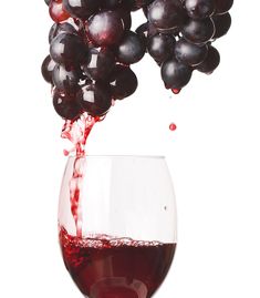 red wine being poured into a glass with grapes on the vine coming out of it