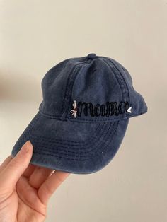 a person holding up a blue hat with embroidered words on it