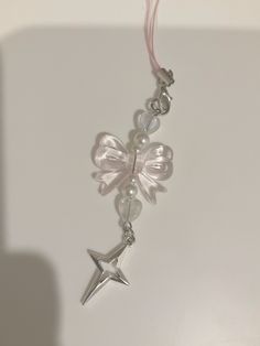 a white necklace with silver stars and pearls on it's end, hanging from a pink cord