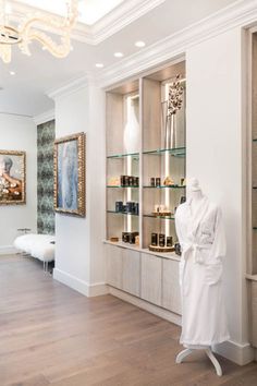 a white robe on display in a room with wood flooring and glass shelves filled with bottles