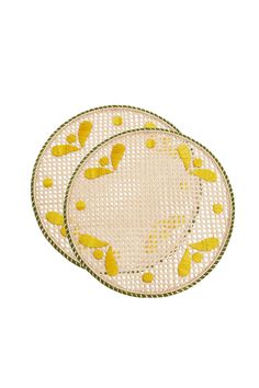 two yellow and white plates sitting next to each other on top of a tablecloth