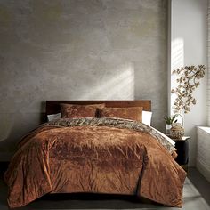 a bedroom with a large bed covered in brown comforter and pillows next to a window