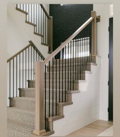 there is a black door and some stairs in the house with white carpet on the floor