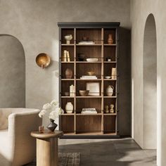 a living room filled with furniture and a book shelf next to a white chair on top of a rug