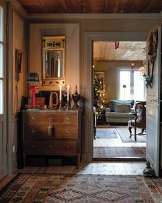 a living room filled with furniture and a christmas tree in the corner near an open door