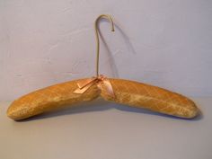 two pieces of bread hang from hooks on a white wall with a pink ribbon tied to it