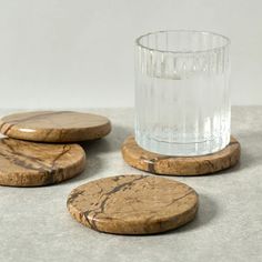 three wooden coasters sitting next to a glass on top of a gray countertop