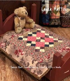 a teddy bear sitting on top of a bed with a quilt in it's arms