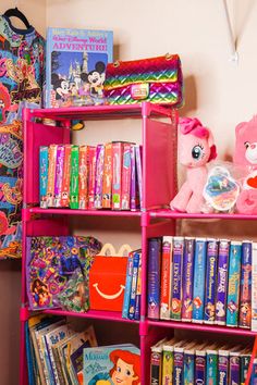 a pink book shelf filled with lots of children's books next to a wall