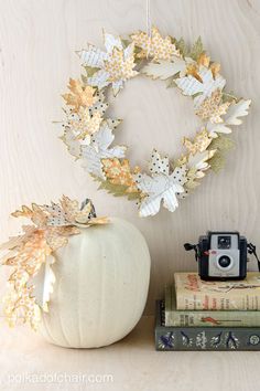 a white pumpkin sitting on top of a wooden table next to books and a camera