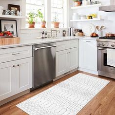 a clean kitchen with white cabinets and stainless steel stove top oven, dishwasher, and sink