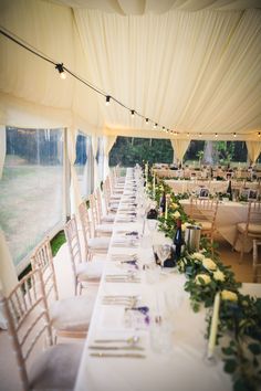 the tables are set up with white linens and greenery for an elegant wedding reception