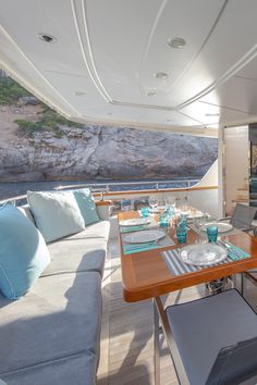 the dining table is set for two on the boat's aft deck, with blue and white pillows