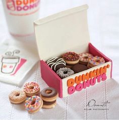 there are many donuts in the box and one is on the table next to a cup