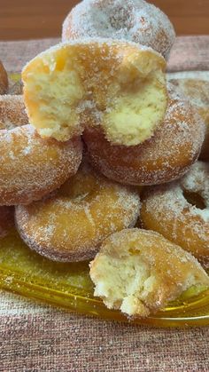 a pile of sugared doughnuts sitting on top of a yellow glass plate