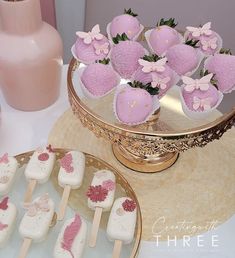 there are many desserts on the table with pink flowers in vases behind them