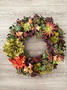 a wreath made out of succulents on a wooden wall with white boards