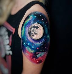 a woman's arm with a colorful tattoo on it and the moon in the sky