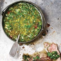 a bowl filled with green soup next to a spoon