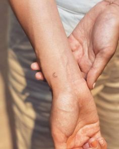 two hands holding each other with one small dot on the left hand and another smaller dot on the right